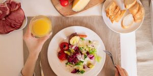 A top-view of a delicious breakfast setting featuring a salad, bread, cheese, tomatoes, and orange juice.